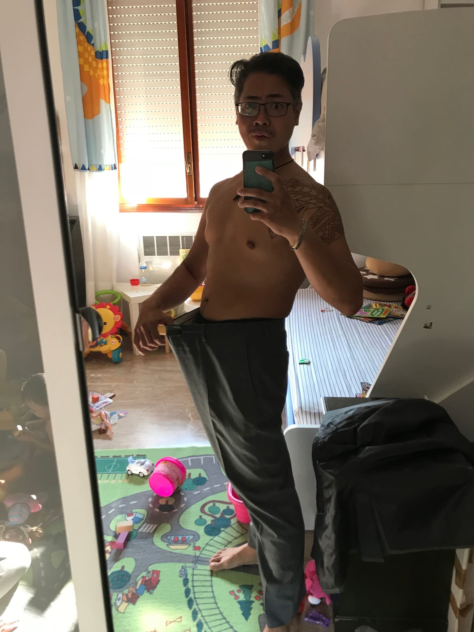 Me holding out the waistband of trousers that used to fit.